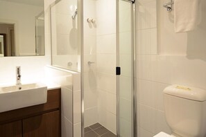 A modern bathroom with a glass shower enclosure, a white sink, and a toilet. - Grosvenor Hotel Adelaide by Accor (Adelaide)