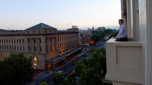 A view of a cityscape with a prominent building featuring a green roof and classical architecture.