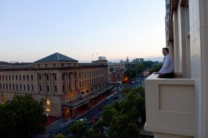Vista de un paisaje urbano con un edificio destacado que tiene un techo verde y arquitectura clásica.