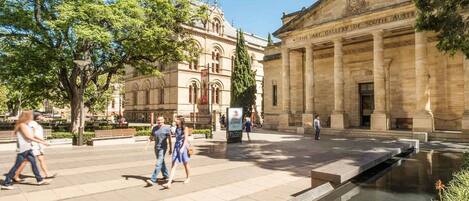 A public square with a classical building labeled 'The Art Gallery of South Australia,' featuring a fountain and pedestrian pathways.