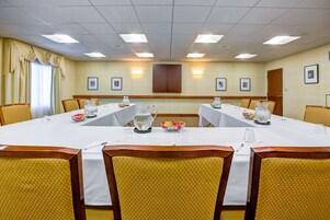 Un salón de conferencias con una mesa larga, sillas y un armario.