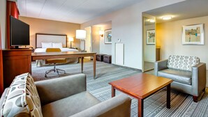 A hotel room with a bed, desk, chair, sofa, and a TV. - Hampton Inn Boston - Norwood (Norwood)
