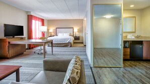 A hotel room with a bed, desk, TV, and a mirror. - Hampton Inn Boston - Norwood (Norwood)