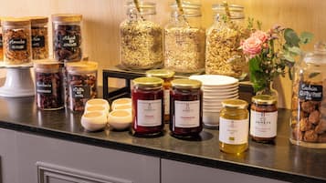 Variedad de alimentos, incluyendo frascos de mermeladas, nueces y frutas secas sobre una encimera.