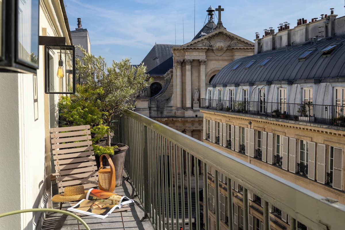 A balcony with a wicker chair, a wicker basket, and a magazine.