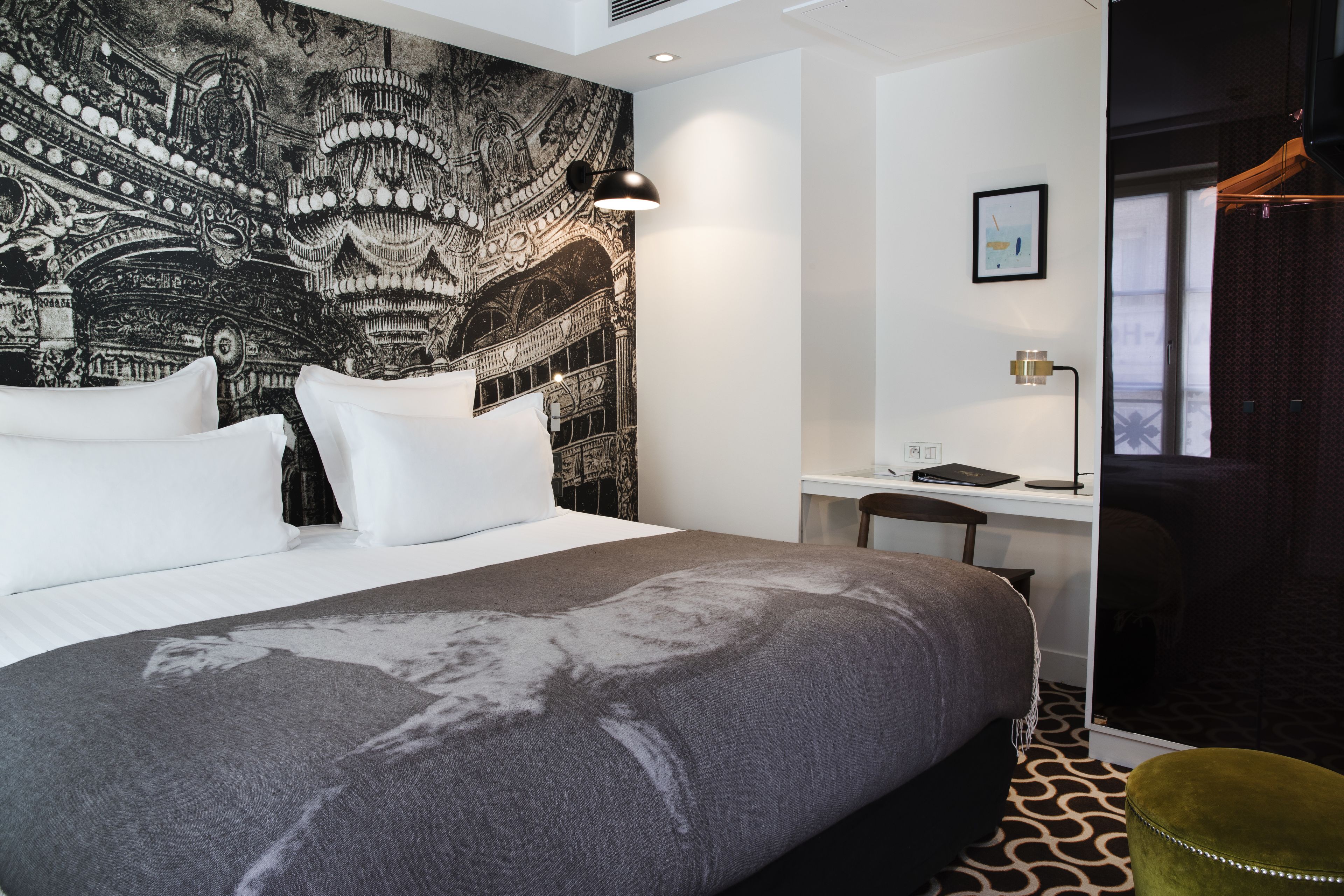 A modern hotel room with a large bed, a desk, and a chair.