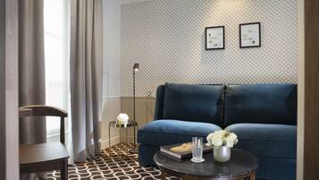 A modern living room with a blue sofa, a round coffee table, a floor lamp, and a patterned carpet.