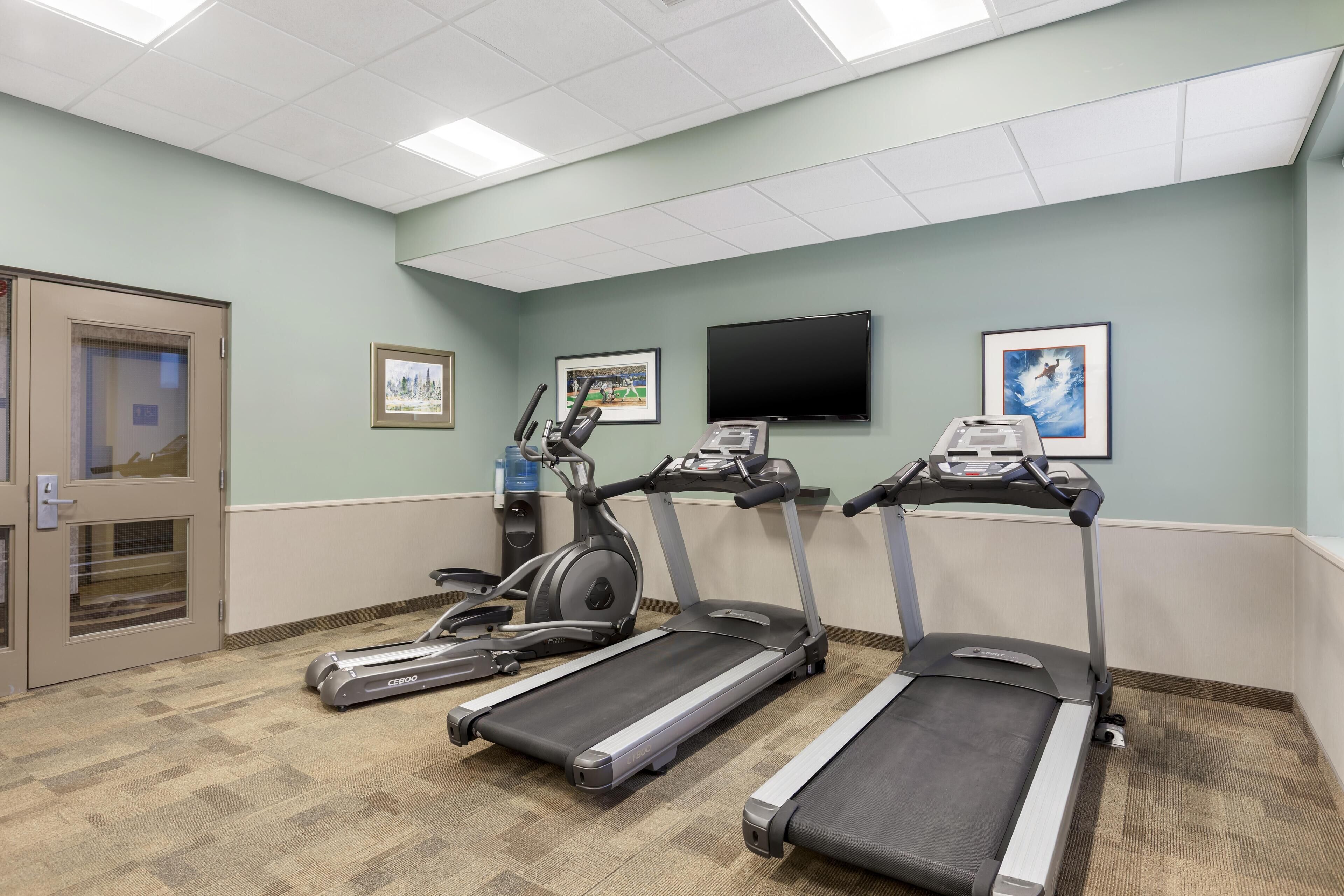 Une salle de remise en forme équipée de tapis de course, d’un vélo elliptique et d’un vélo d’appartement.