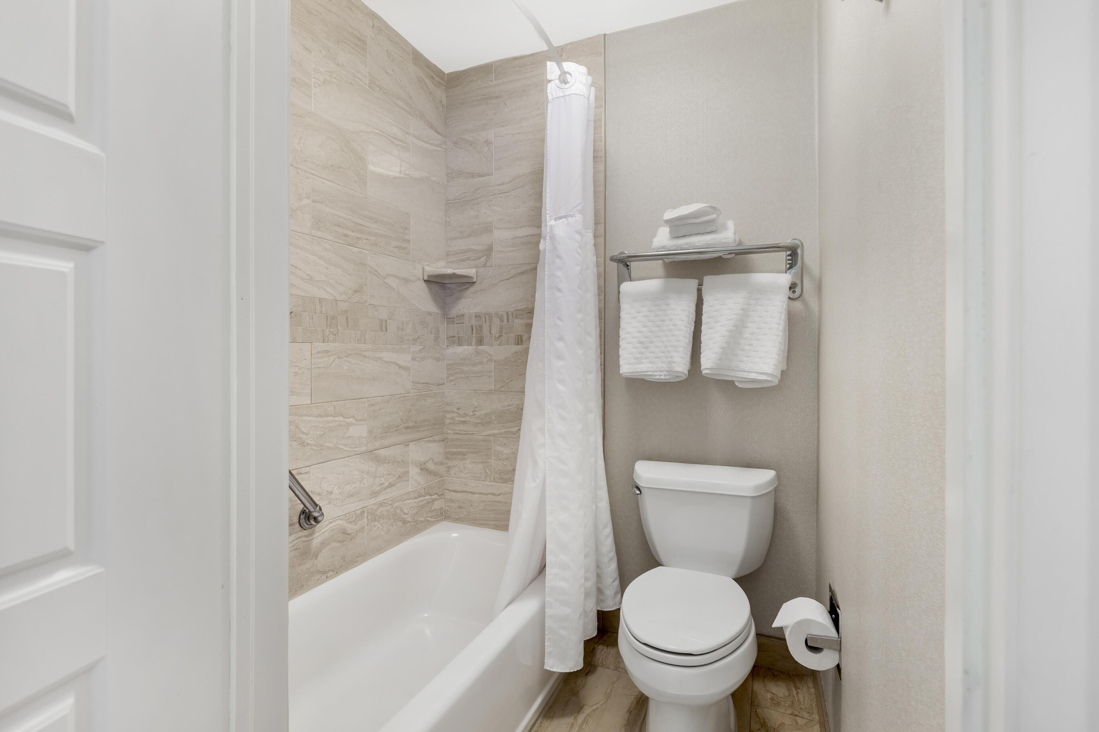 Een moderne badkamer met bad, toilet en douchegordijn.