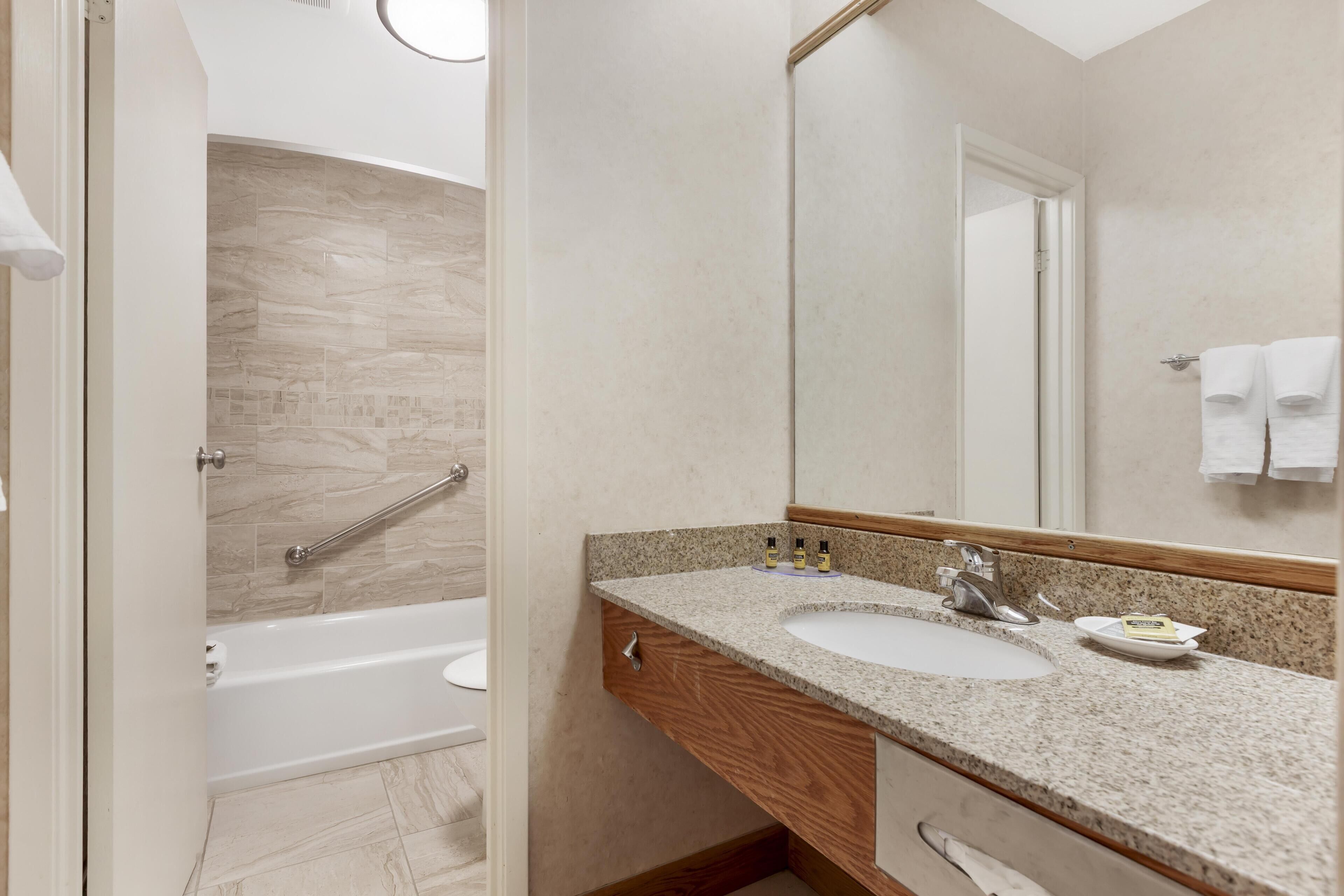 A bathroom with a bathtub, a sink, and a mirror.
