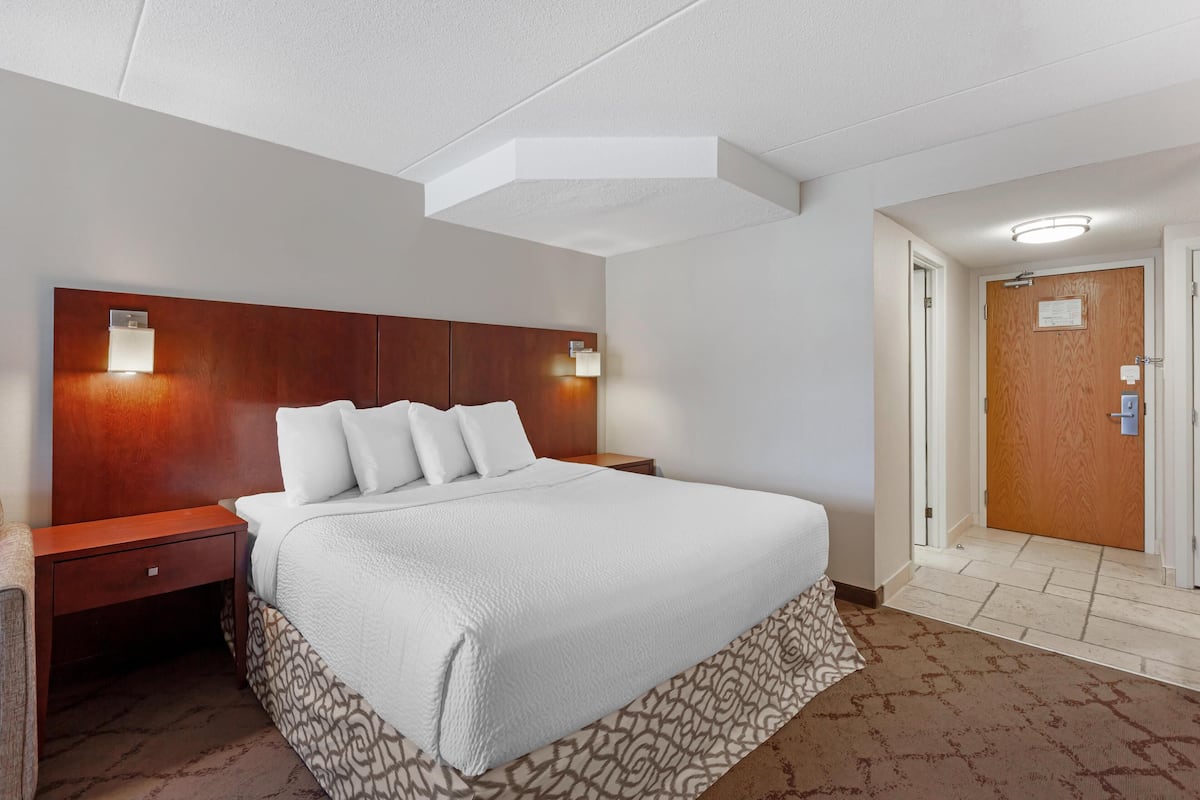 Ein Hotelzimmer mit einem großen Bett, zwei Nachttischen, einem Holz-Kopfteil und einer Tür mit einer Holztürfüllung.