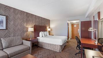 Una habitación de hotel con cama, sofá, escritorio y silla.