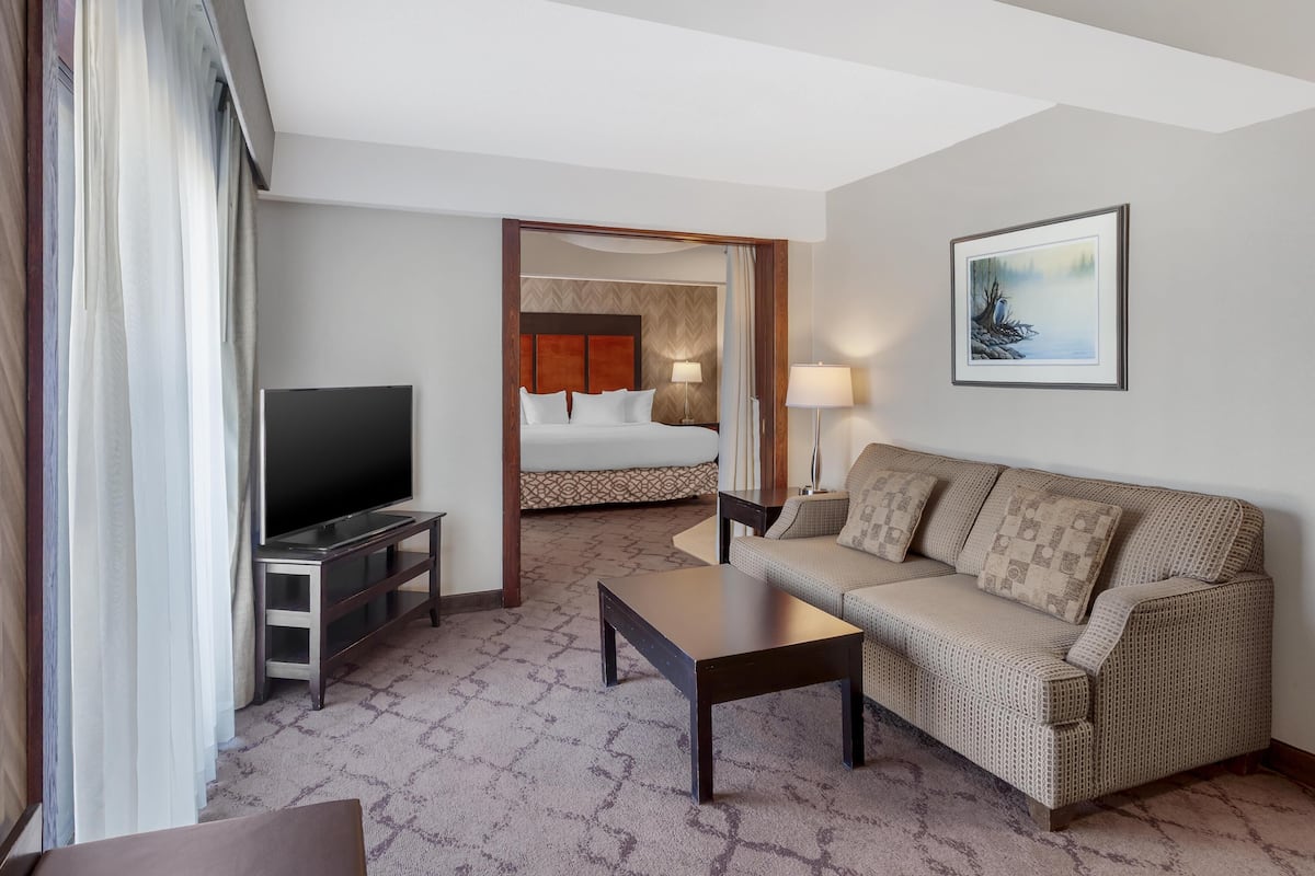 Ein Hotelzimmer mit einem Bett, einem Fernseher, einem Sofa, einem Couchtisch und einem Bild an der Wand.