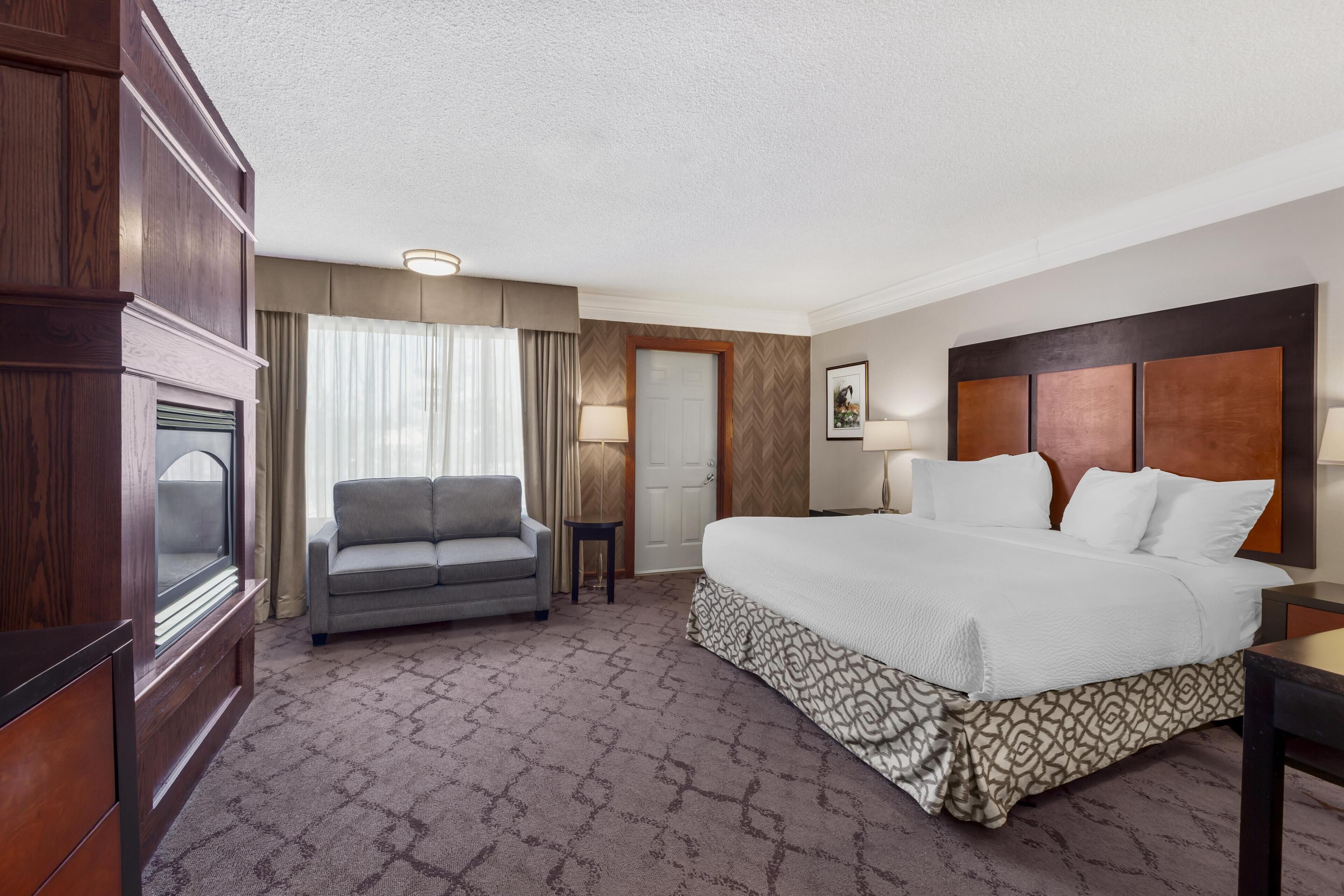 A hotel room with a large bed, a sofa, a small table, and a door.