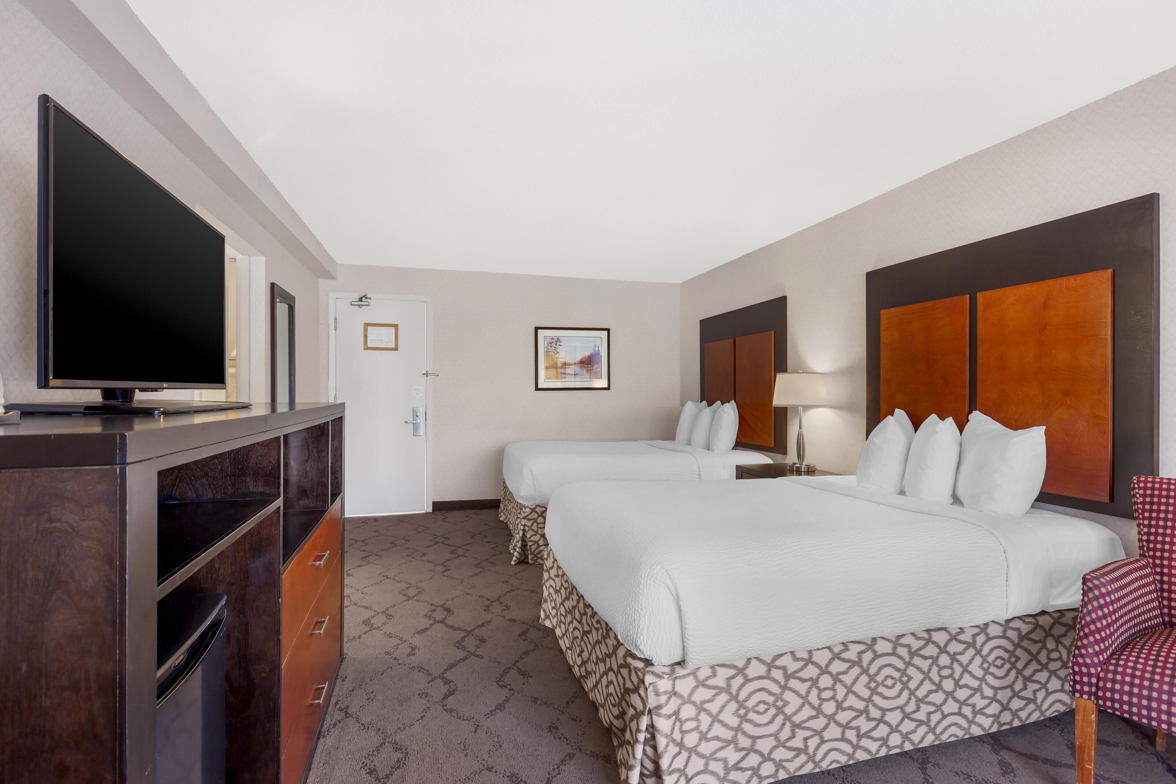 Habitación de hotel con dos camas, televisor, escritorio y una silla.