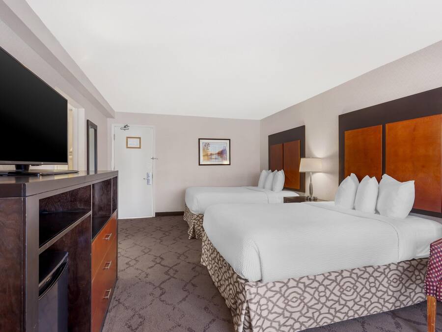 Habitación de hotel con dos camas, televisor, escritorio y una silla.