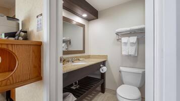 A modern bathroom with a wooden vanity, two sinks, a toilet, and a towel rack.