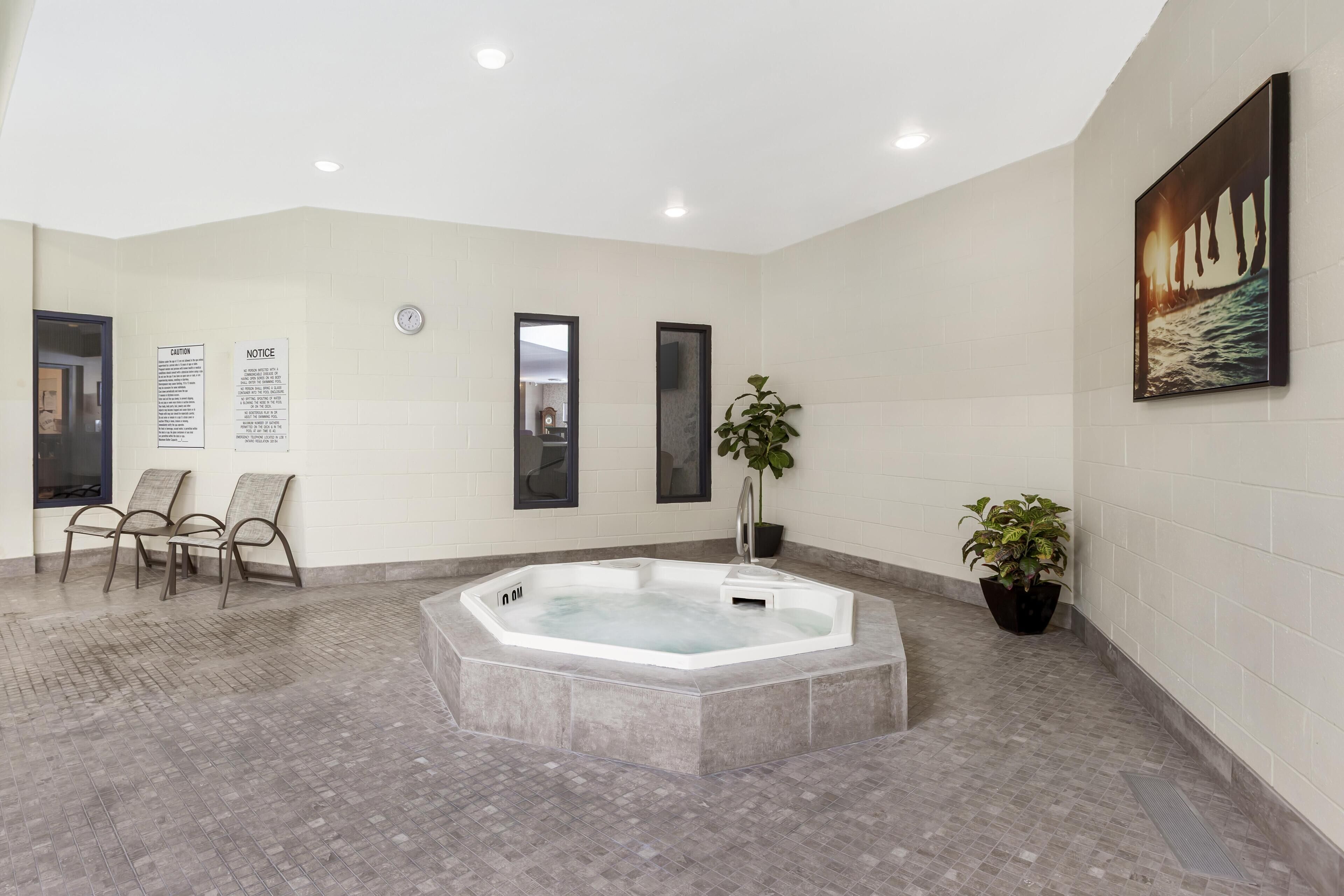 Un baño moderno con una bañera independiente, dos espejos montados en la pared, un reloj y un cuadro enmarcado.