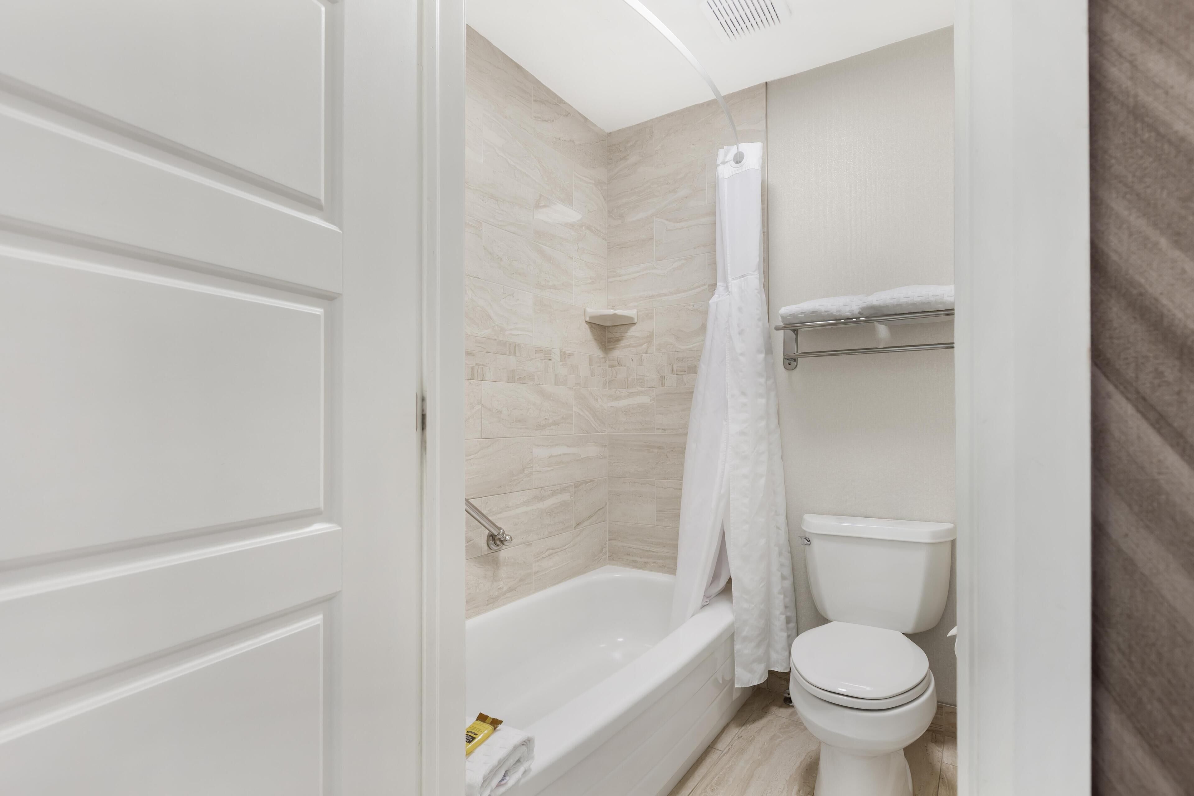 A bathroom with a bathtub, toilet, and shower curtain.