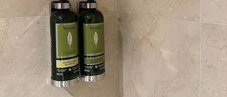 Two bottles of Vervine shampoo and shower gel on a tiled wall.