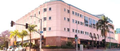 A pink multi-story building with a flat facade, multiple windows, and a corner entrance.
