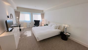 Une chambre d’hôtel avec un grand lit, un bureau avec un ordinateur, une chaise, une petite table et une lampe.