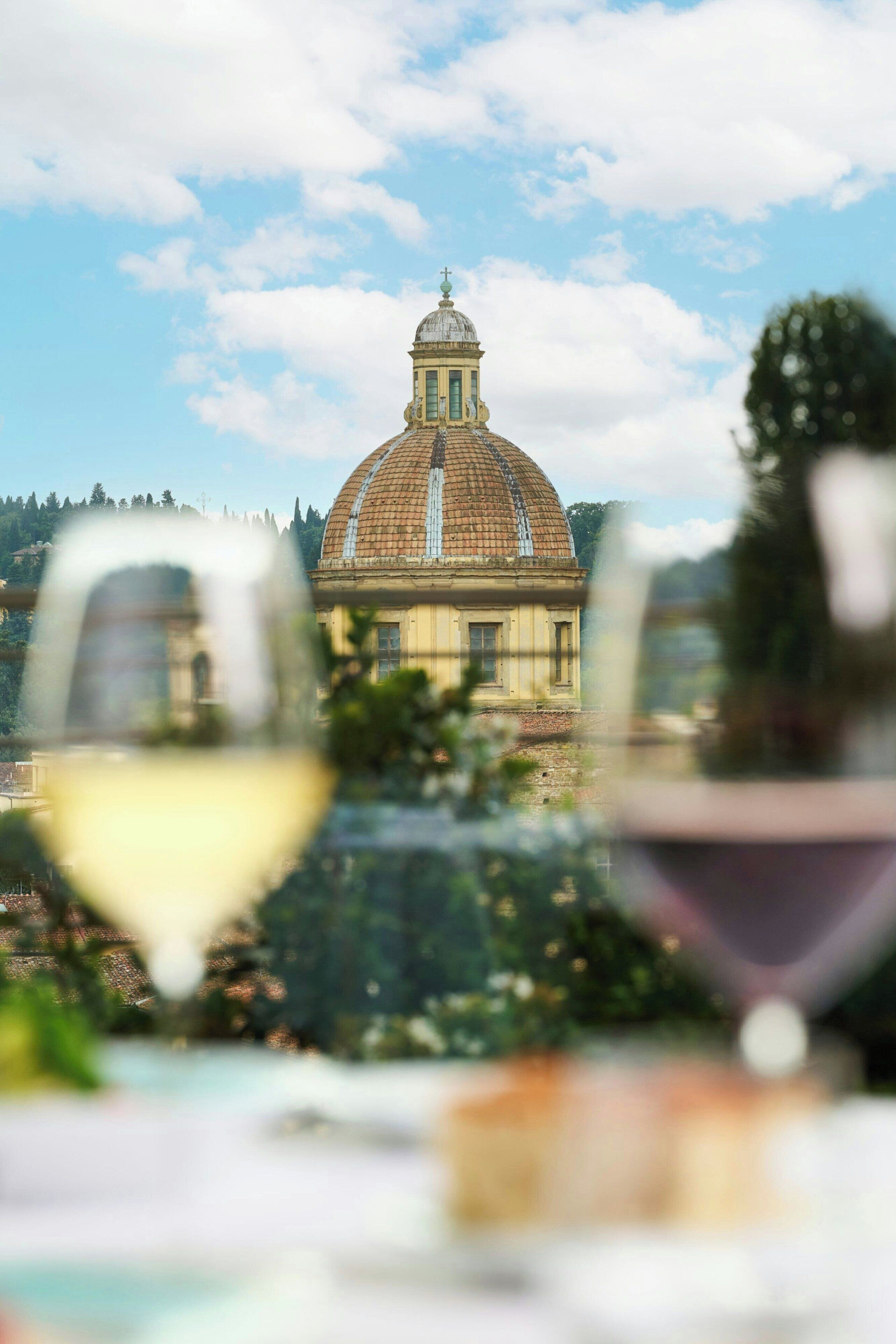 Une vue d’un bâtiment doté d’un dôme et d’une tour, capturée à travers le verre d’un verre à vin.