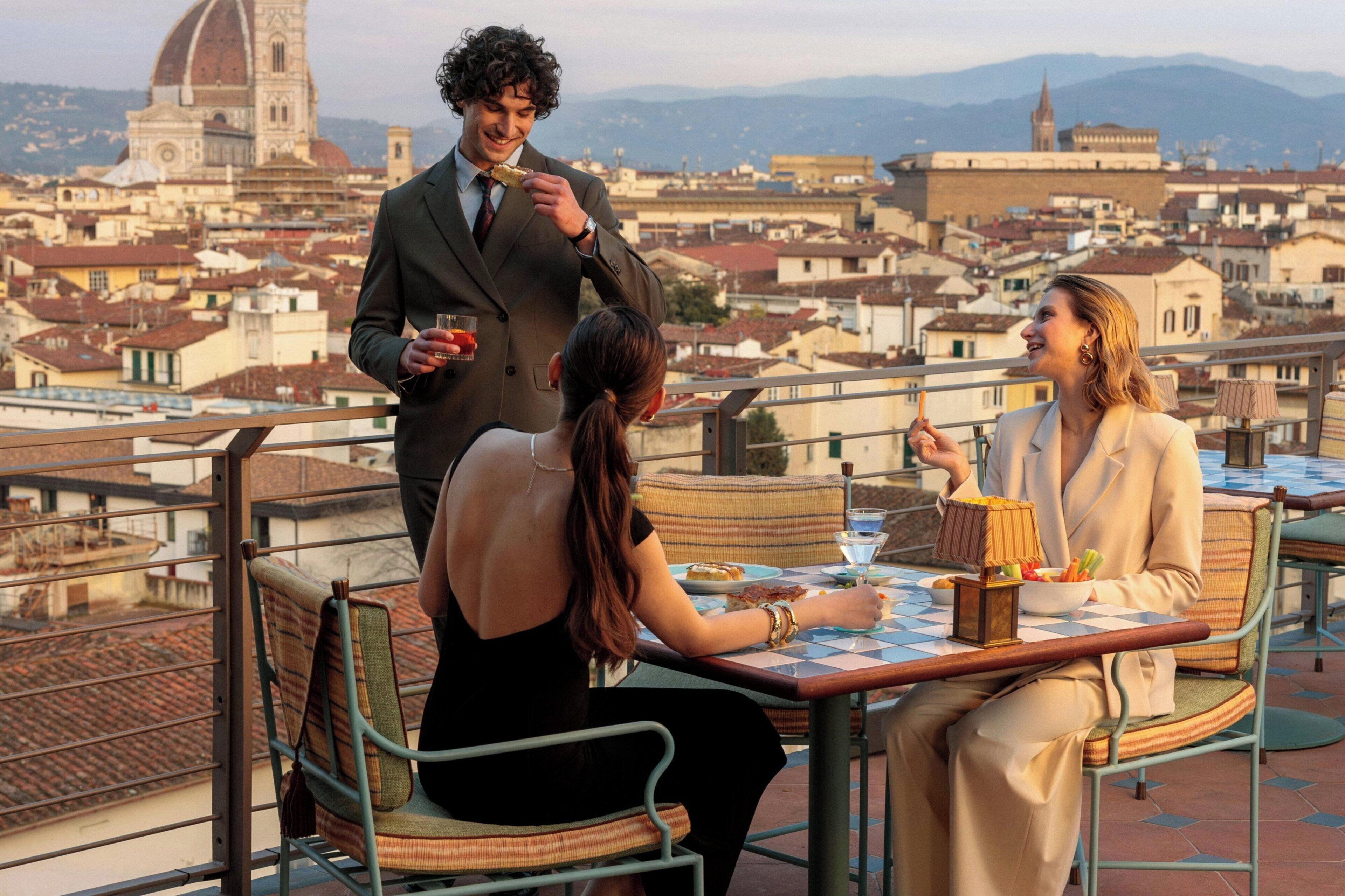 Una terrazza con un tavolo apparecchiato per due, affacciata su un panorama urbano con edifici storici.