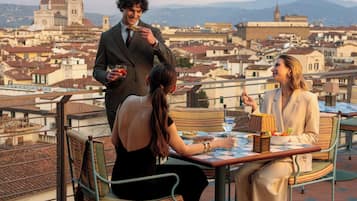 Una terrazza con un tavolo apparecchiato per due, affacciata su un panorama urbano con edifici storici.