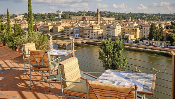 A terrace with chairs and a table, overlooking a river and a cityscape with historic buildings. - The Excelsior, a Luxury Collection Hotel, Florence (Florence)
