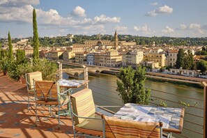 A terrace with chairs and a table, overlooking a river and a cityscape with historic buildings. - The Excelsior, a Luxury Collection Hotel, Florence (Florence)