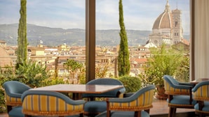 A dining area with tables and chairs, overlooking a cityscape with a prominent cathedral. - The Excelsior, a Luxury Collection Hotel, Florence (Florence)