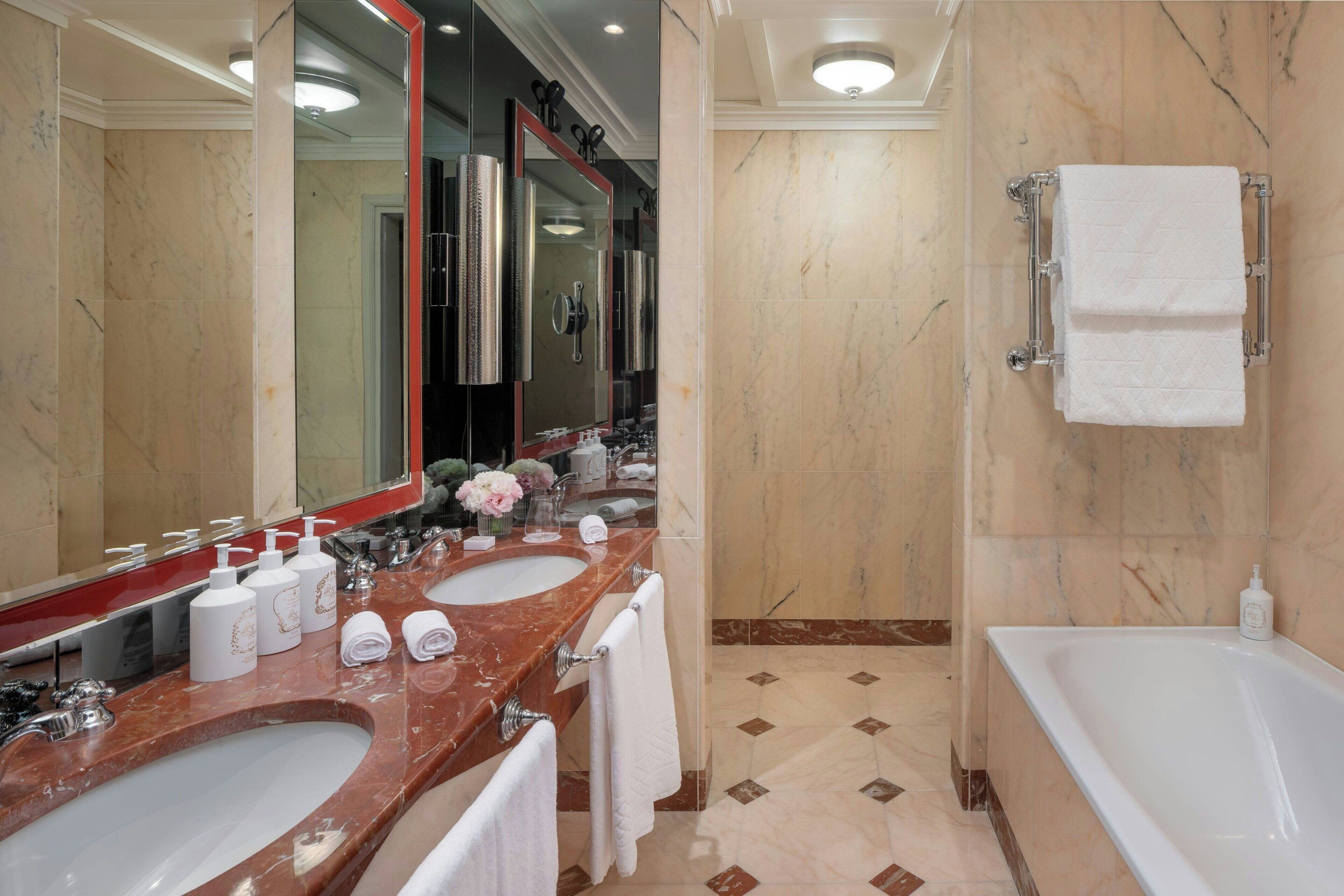 Un baño moderno con dos lavamanos, un espejo grande, una bañera y una zona de ducha.