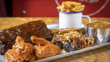 A tray with ribs, chicken wings, and a side of beans.