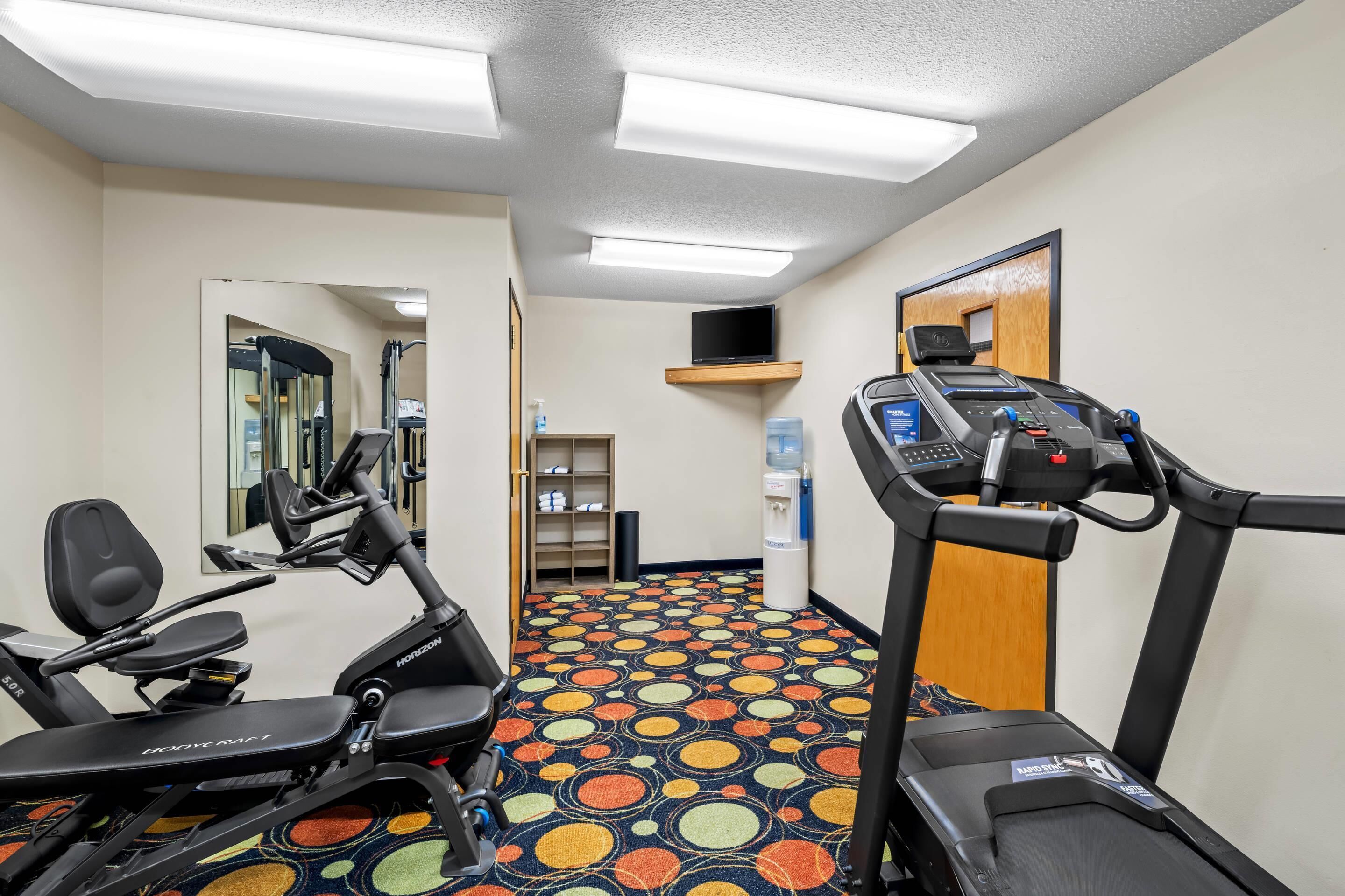 A fitness center with treadmills, ellipticals, and a colorful patterned floor.