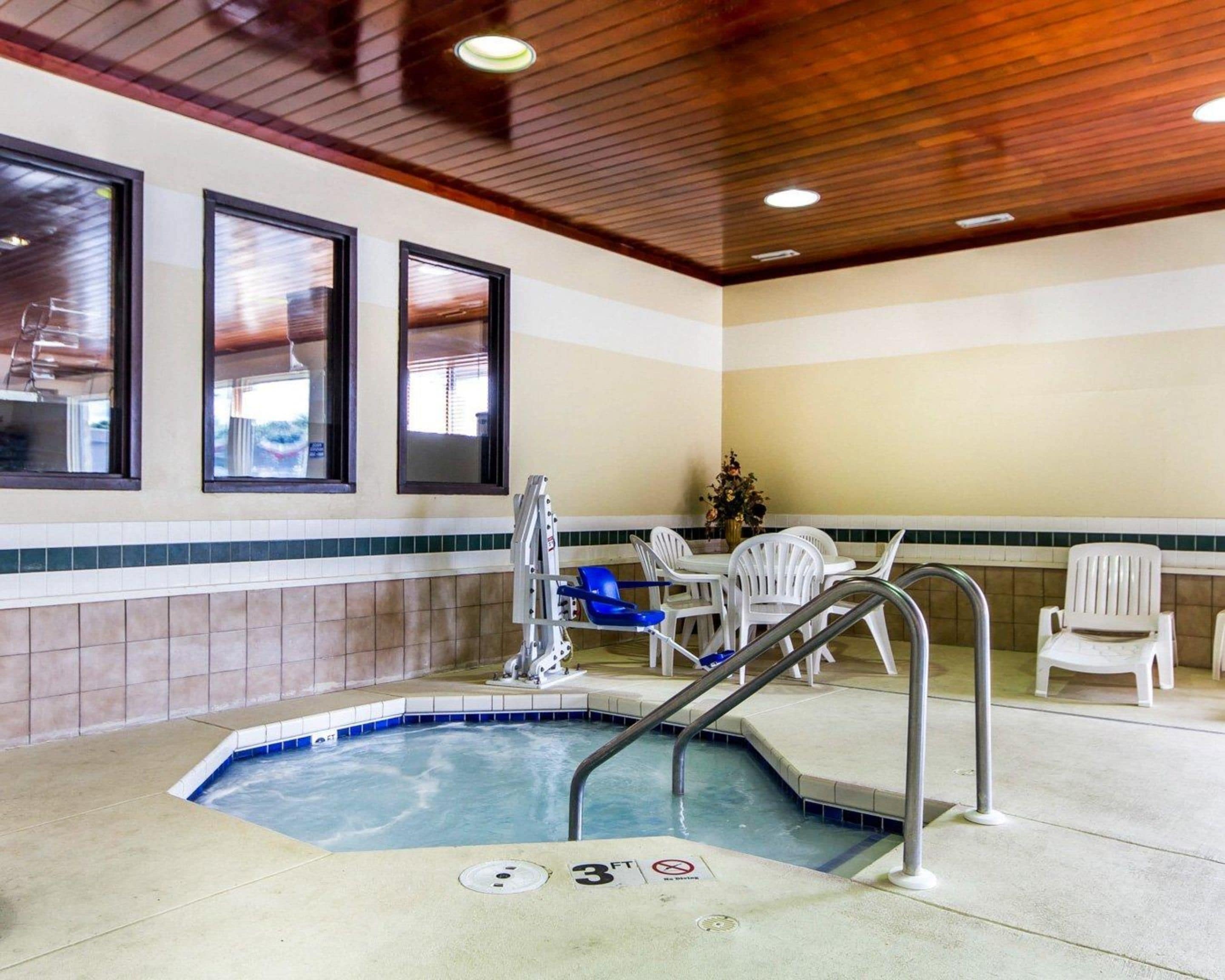 Un espace piscine comprenant un jacuzzi, une chaise longue et une table avec des chaises.
