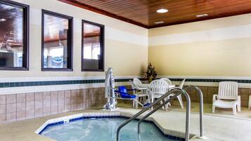 A pool area with a hot tub, a lounge chair, and a table with chairs.