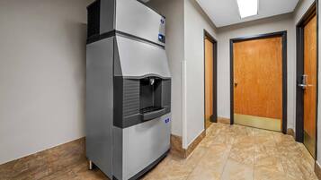 A hallway with a commercial refrigerator, a wooden door, and a tiled floor.