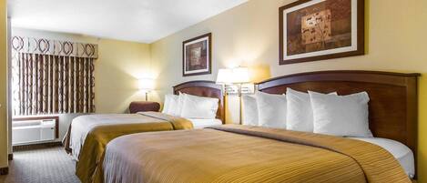 A hotel room with two beds, a large window with curtains, a wall-mounted artwork, and a lamp.