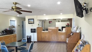 A spacious indoor area with a reception desk, a dining table with chairs, a ceiling fan, and a television mounted on the wall. - Americas Best Value Inn Sullivan (Sullivan)