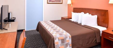A hotel room with a bed, a desk, a chair, a television, and a door.