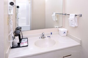 Un baño de hotel con lavamanos, secador de pelo, espejo y toallero.