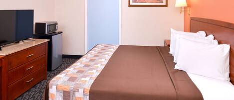Una habitación de hotel con una cama, televisor, microondas, cómoda y una puerta.