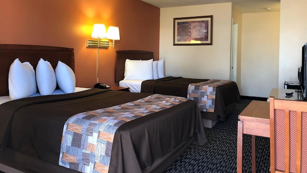 A hotel room with two beds, a desk, a chair, a lamp, and a painting on the wall. - Americas Best Value Inn Sullivan (Sullivan)