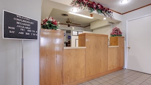 A reception area with a wooden reception desk, a sign indicating complimentary breakfast availability, and a ceiling fan. - Americas Best Value Inn Sullivan (Sullivan)