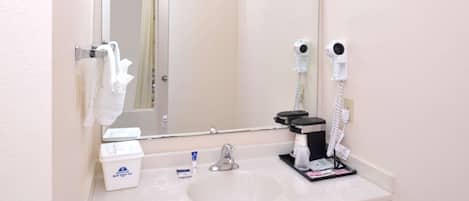 Un baño con lavamanos, espejo, toallero y secador de pelo.