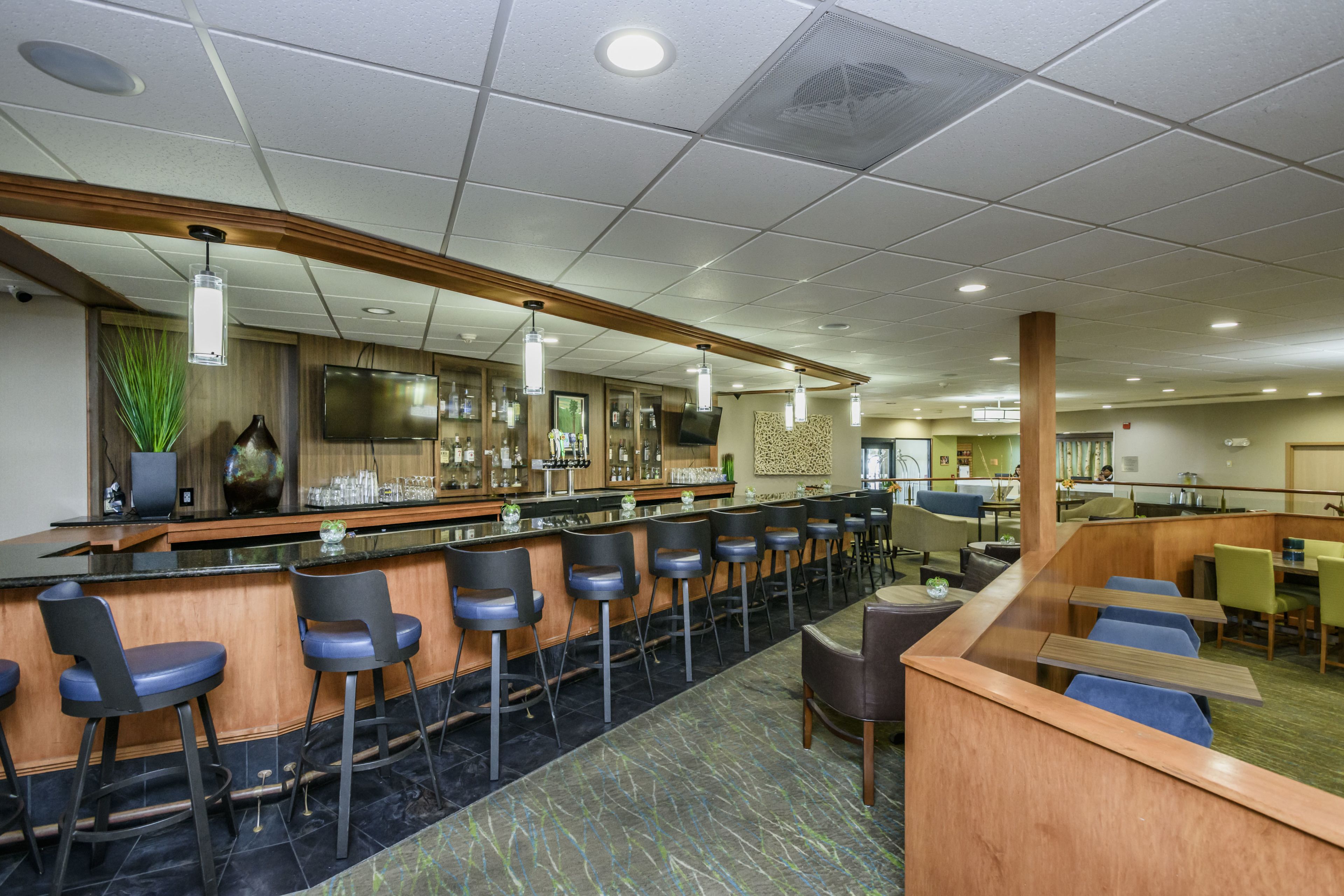 A bar area with multiple stools, a counter, and a television screen.