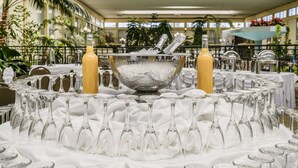 A banquet table with a large bowl, two bottles, and numerous wine glasses arranged around it. - Wyndham Garden Fresno Yosemite Airport (Fresno)