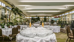 An indoor dining area with round tables covered in white tablecloths, arranged in a semi-circle. - Wyndham Garden Fresno Yosemite Airport (Fresno)