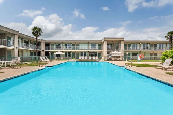 Guests can enjoy a refreshing swim in the hotel's central pool surrounded by lounge chairs and umbrellas.